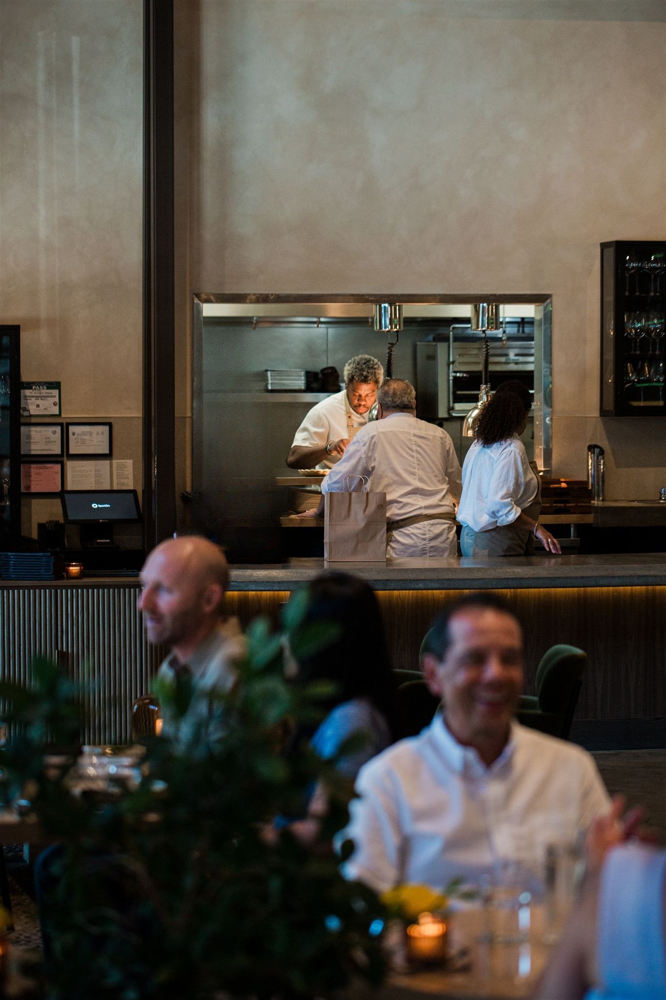 Diners in the dining room with the open kitchen pass behind